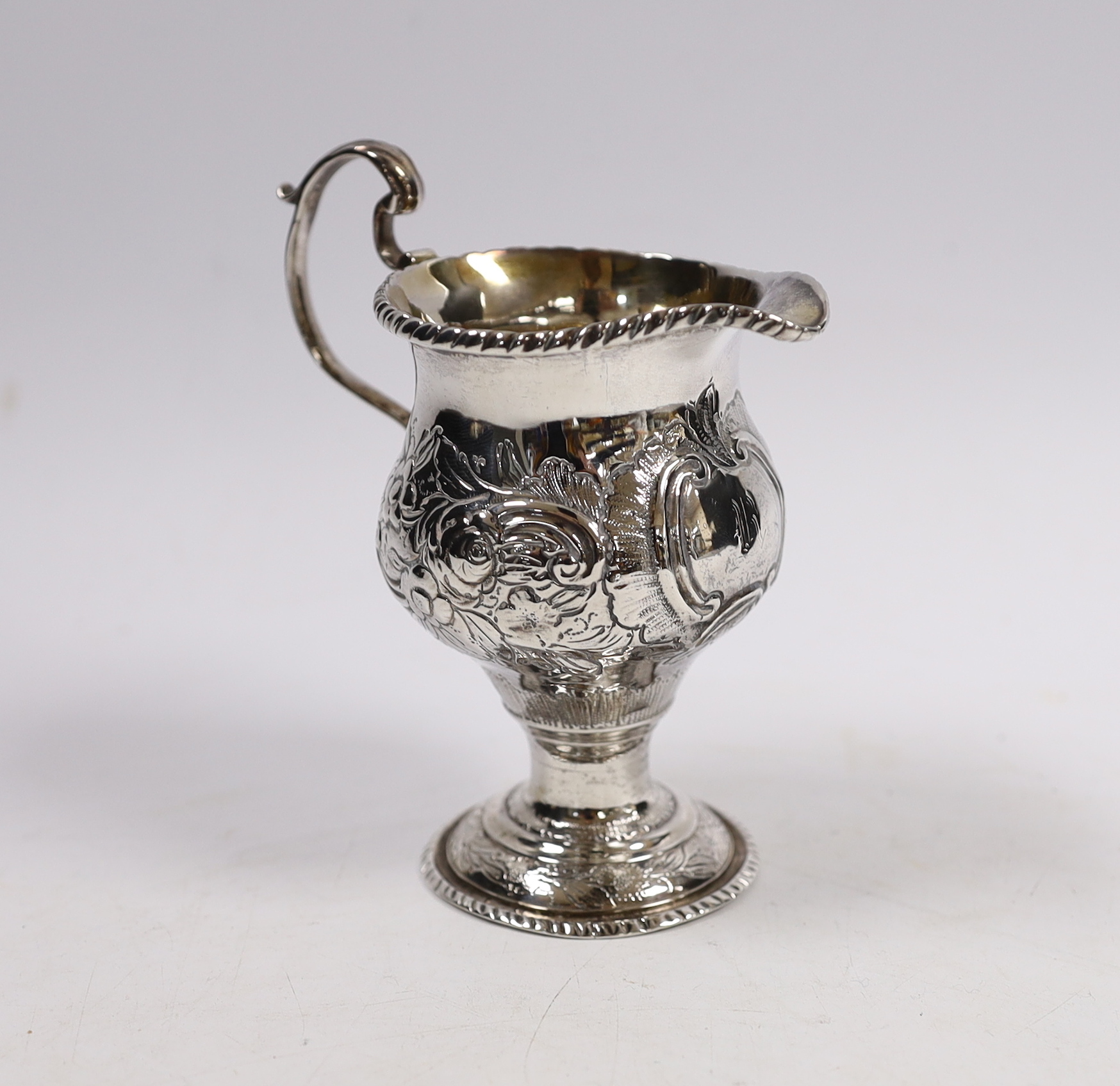 An early George III silver inverted pear shaped cream jug, with later embossed decoration, London, 1764, 11.5cm.